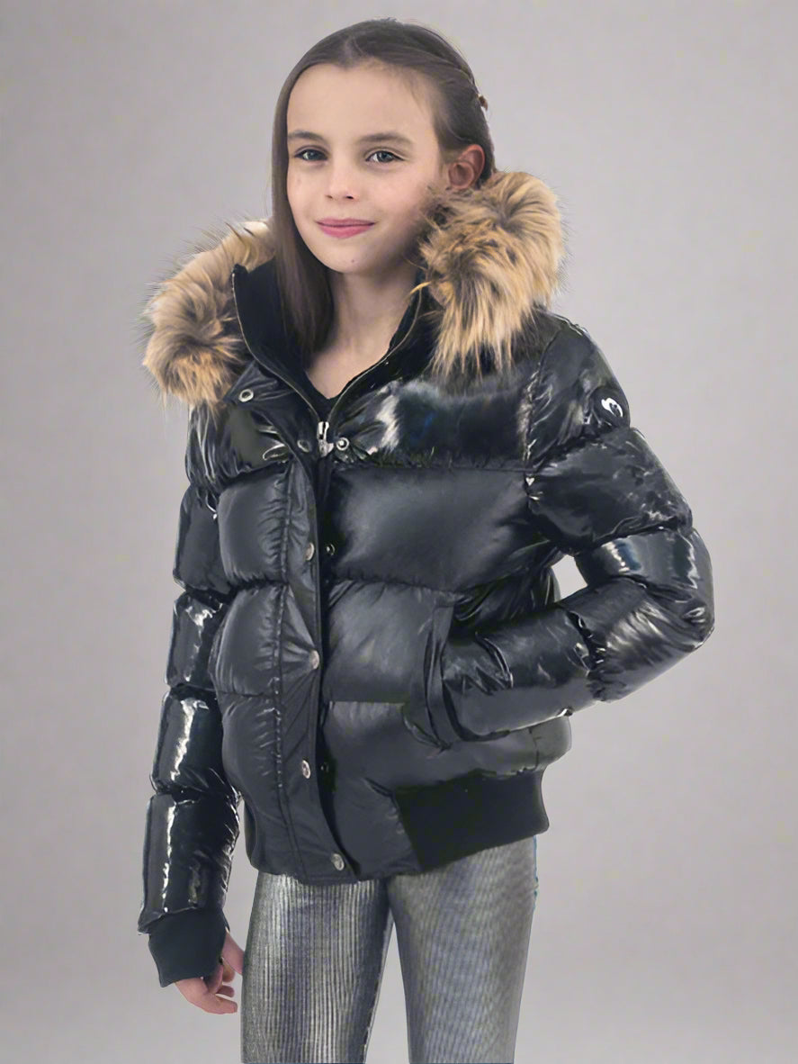Girl wearing a black puffer jacket with fur hood on a gray background
