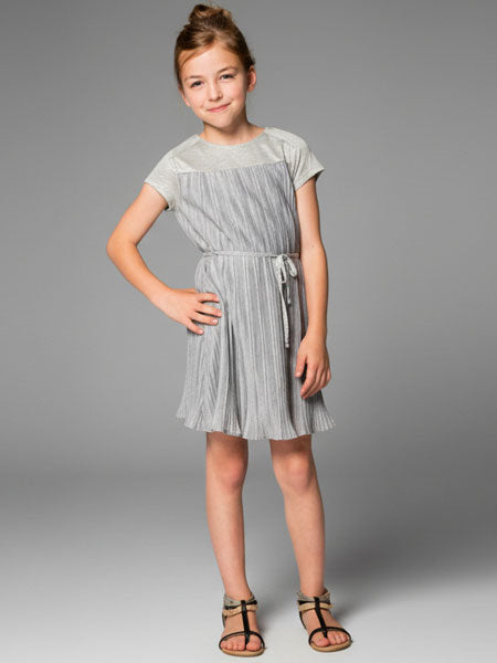 Young girl wearing a light gray dress with a belt on a gray background