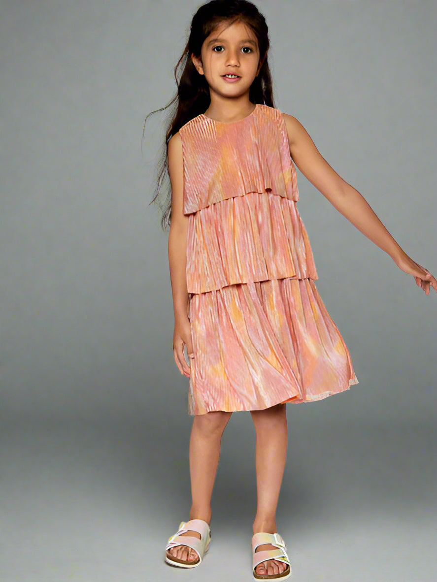 Girl modeling metallic rainbow print, this pleated party dress features a sleeveless bodice with wide straps, a round neckline, and three separate tiers. By Deux Par Deux.