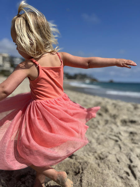 Back view of a coral colored tutu dress with tank style jersey knit top.