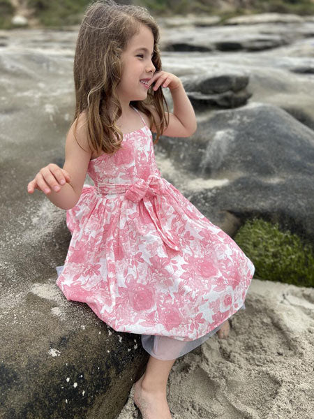 Sleeveless, thin straps, girls party dress in a pink roses print by Vignette. Soft mesh white tulle at hem.