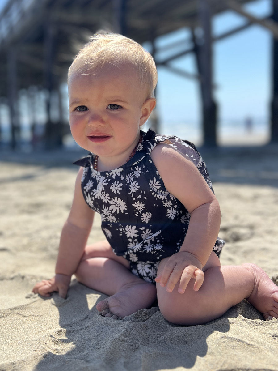 Baby girls bubble romper. Black with with daisies, sleeveless.