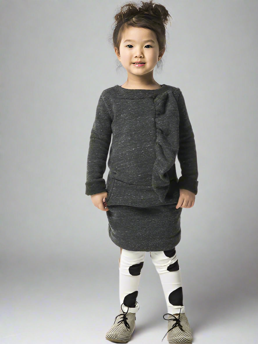 Child wearing a dark gray dress with ruffles on a gray background