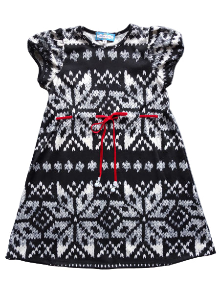 A black and white snowflake patterned dress with short sleeves and a red velvet ribbon tie at the waist on a toddler.