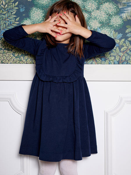 Girl modeling navy blue long sleeve girls cotton jersey dress. Ruffle trim.