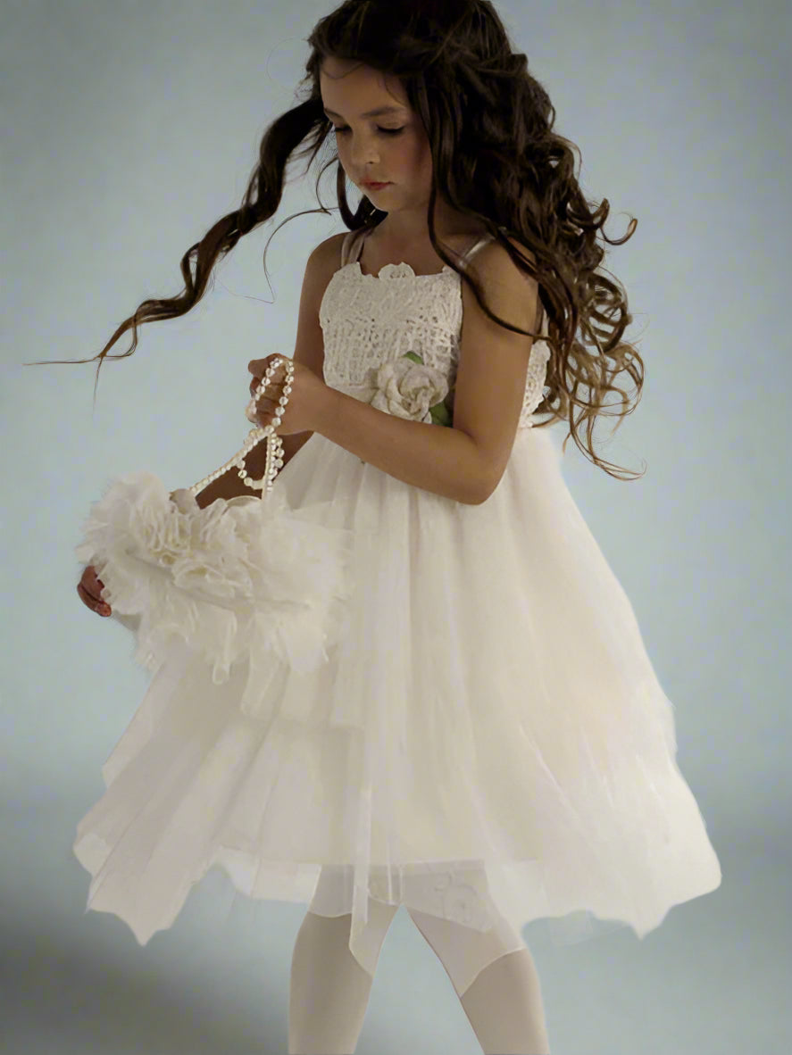 Young girl in a white dress holding a bouquet against a light gray background