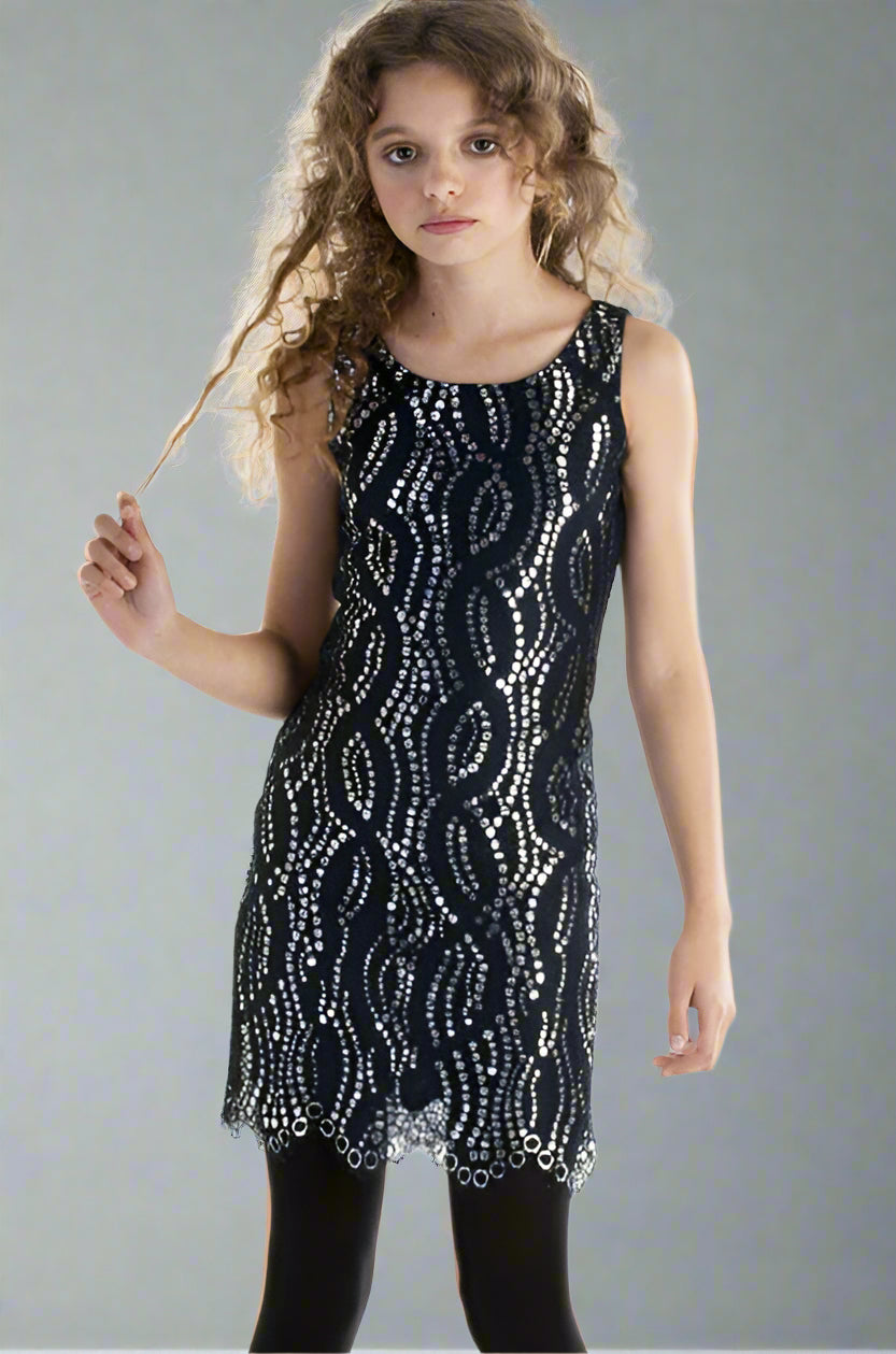 Young girl wearing a navy dress with white patterns against a gray background