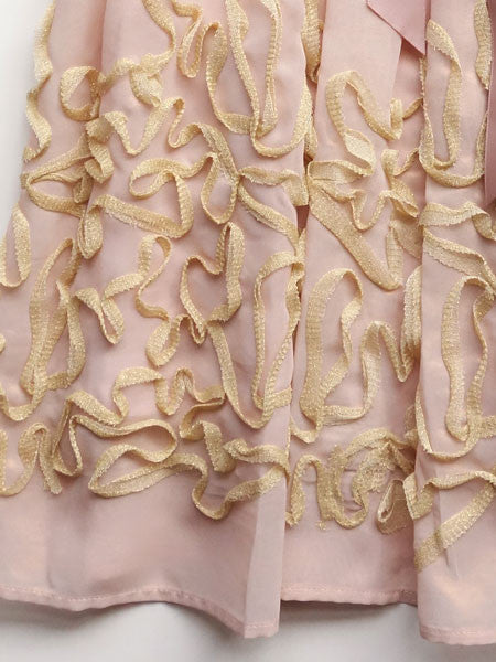 Blush pink chiffon dress embellished with gold metallic lace on skirt, pink satin ribbon belt at waist. Sleeveless. Blush by Us Angels girls party dress.