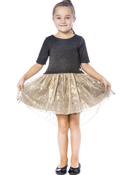 Little girl posing in a high low party dress by Deux par Deux. Black metallic knit top with gold chiffon skirt over black tulle. Skirt is scattered with small silver squares. Round scoop neck with back bow.