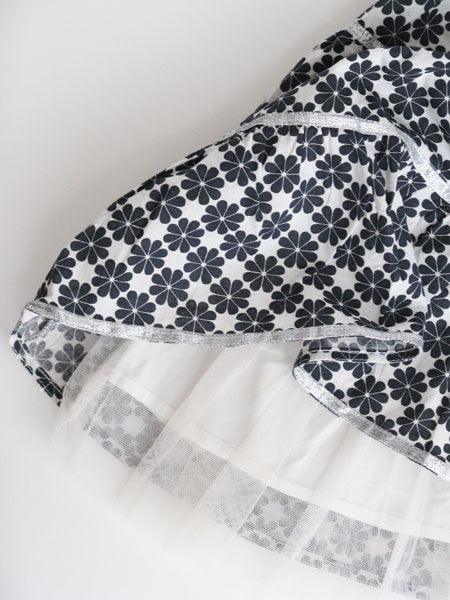 Detail of slate gray and white abstract clover print little girls party dress. Tiered. Metallic ribbon and thread accents.