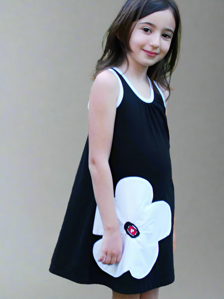 Girl modlelng black summer tank swing style dress. White flower applique on front side of dress.