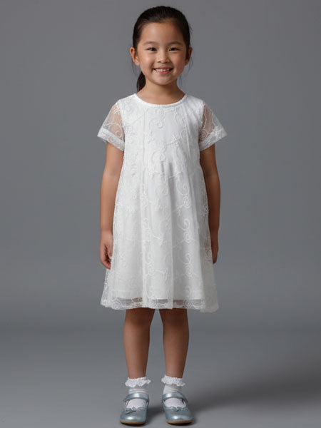 Young girl wearing a white lace dress against a gray background