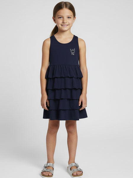 Young girl wearing a navy blue tiered dress on a white background