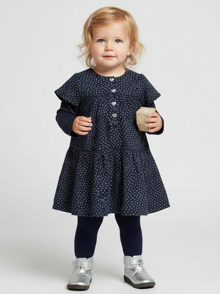 Child wearing a navy dress with white polka dots on a white background