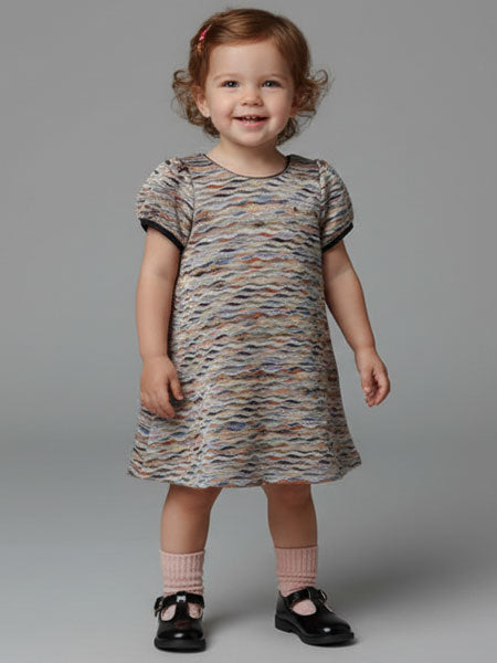 Child wearing a patterned dress on a gray background