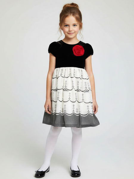 Young girl wearing a black and white dress with a red flower on a white background