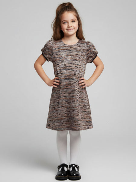 Young girl wearing a patterned dress on a plain background
