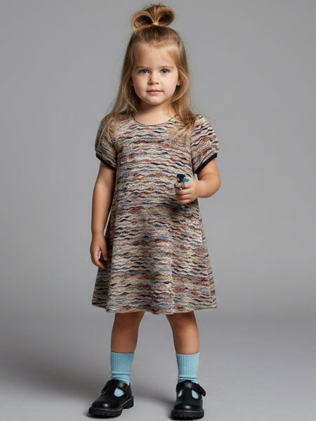 Young girl wearing a patterned dress against a gray background