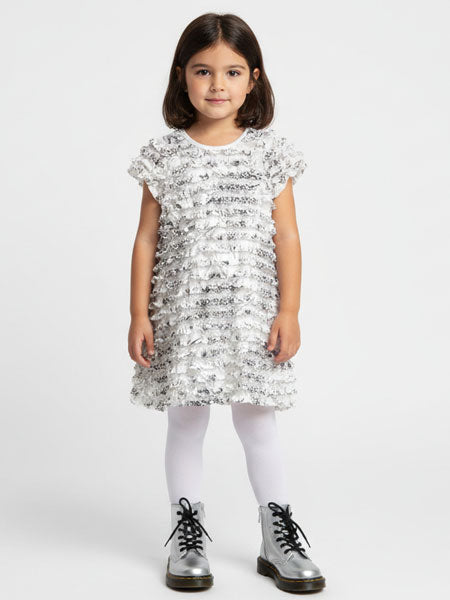 Young girl wearing a white dress with black patterns and silver shoes on a white background