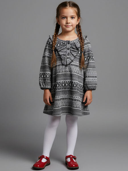 Young girl wearing a patterned dress with red shoes on a gray background