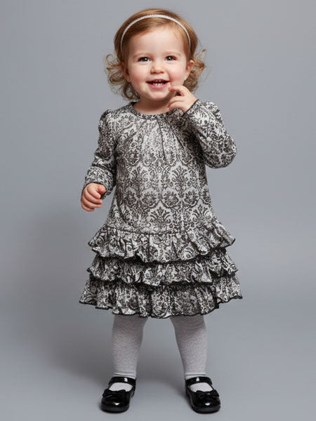 Child wearing a damask patterned dress on a plain background