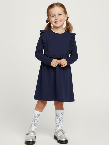 Young girl wearing a navy dress with ruffled sleeves on a white background