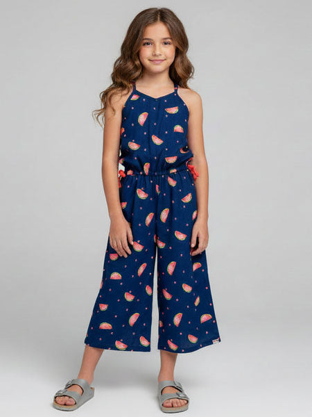 Girl wearing a navy blue jumpsuit with pink watermelon pattern on a gray background
