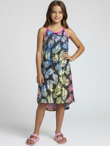 Young girl wearing a colorful tropical leaf patterned dress on a white background