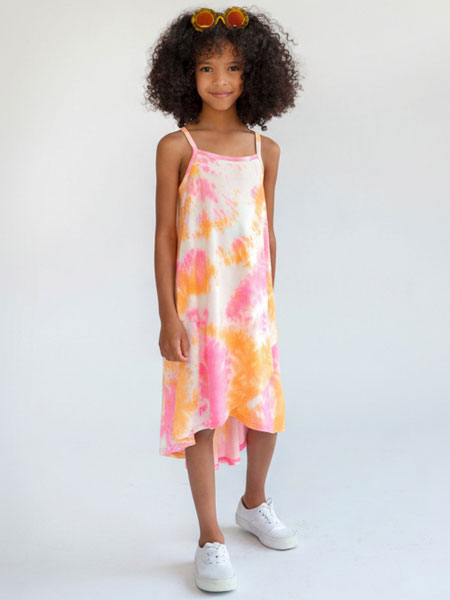 Young girl wearing a tie-dye dress with pink and orange patterns on a white background