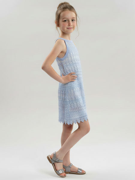 Young girl wearing a light blue dress with a textured pattern on a white background
