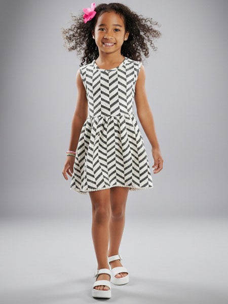Young girl wearing a black and white zigzag dress on a gray background
