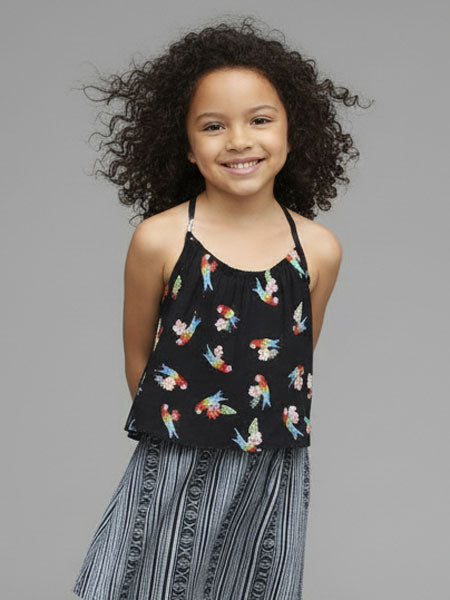 Young girl wearing a black top with colorful parrot pattern against a gray background