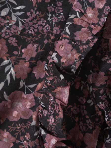 Detail of the fabric, A-line silhouette girls party dress. Black floral print. Small ruffled hem. The brand is Creamie.
