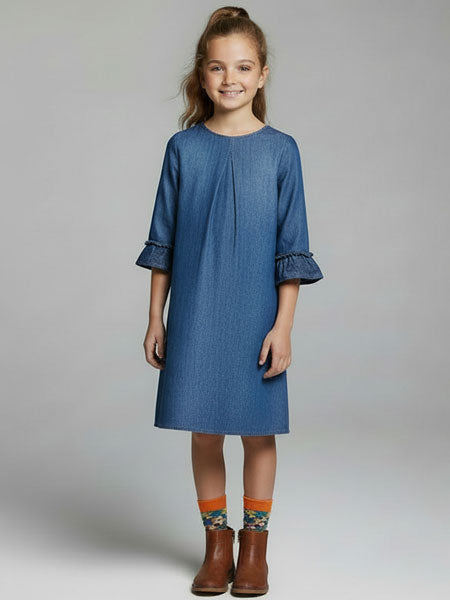 Young girl wearing a blue dress with ruffled sleeves on a plain background