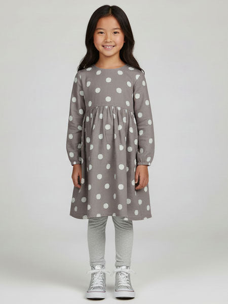 Young girl wearing a gray dress with white polka dots on a white background