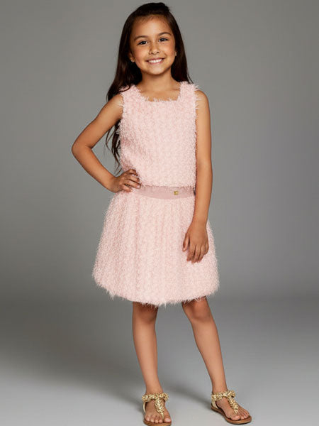 Young girl wearing a pink dress with a textured pattern on a gray background