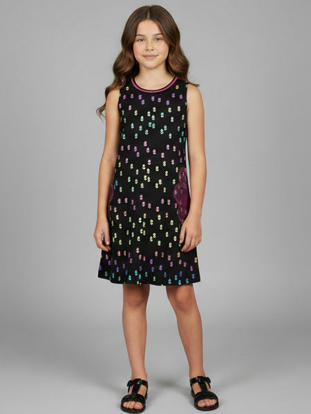 Young girl wearing a black sleeveless dress with colorful pattern on a gray background