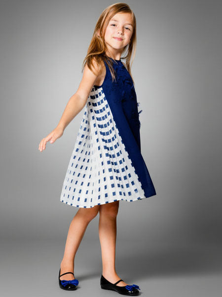 Young girl wearing a blue and white dress against a gray background