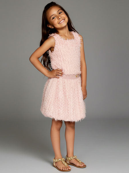 Young girl wearing a pink dress against a gray background