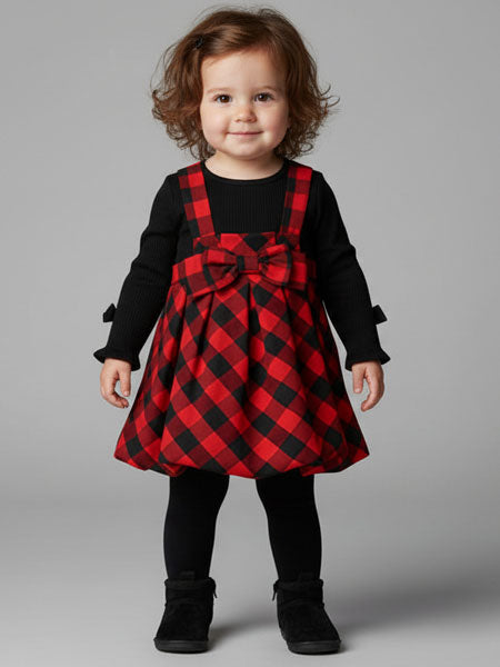 Child wearing a red and black checkered dress with a large bow on a gray background