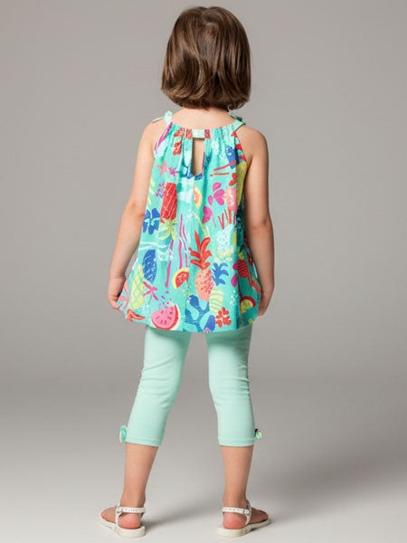 Child wearing a colorful tropical-themed top and light green pants on a gray background