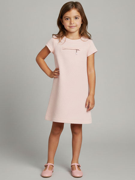 Young girl wearing a pink dress against a gray background