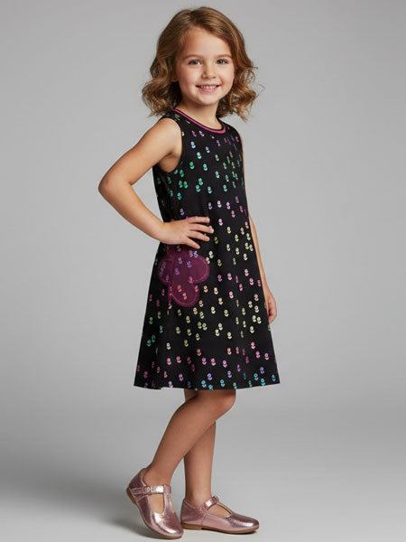 Young girl wearing a black dress with colorful patterns on a gray background