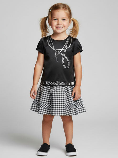 Young girl wearing a black t-shirt with white graphics and a checkered skirt on a light gray background