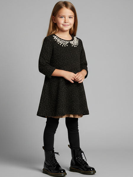 Young girl wearing a black dress with decorative neckline on a gray background