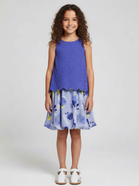Young girl wearing a blue sleeveless top and floral skirt on a white background