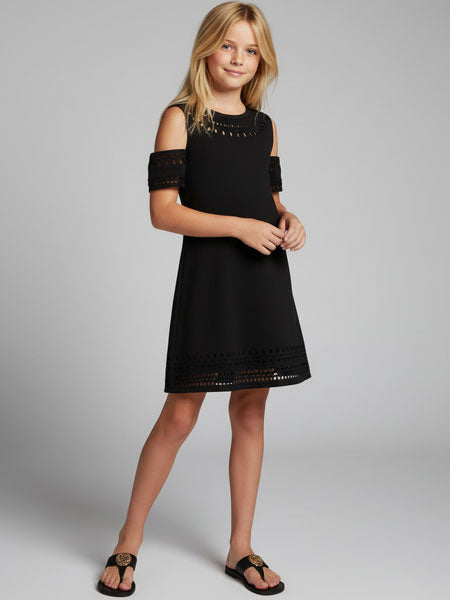 Young girl wearing a black dress with cut-out shoulders on a gray background