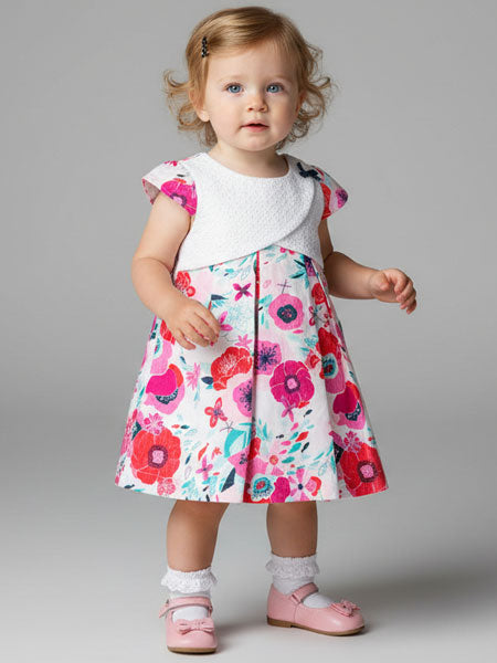 Child wearing a colorful floral dress on a gray background