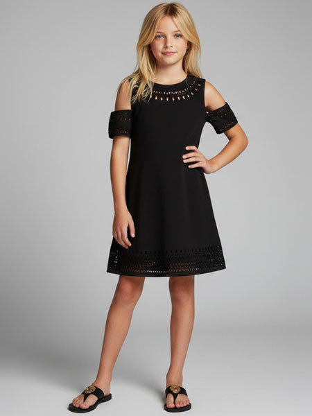 Young girl wearing a black dress with embellishments on a gray background