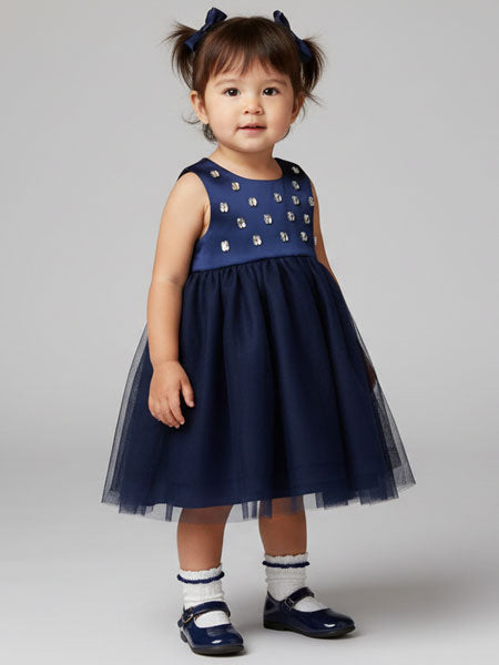 Child wearing a navy blue dress with fax gemstones on a gray background